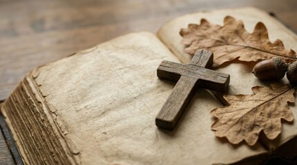 Rustic autumn still life with wooden cross oak leaves and acorn on ancient book pages for spiritual reflection