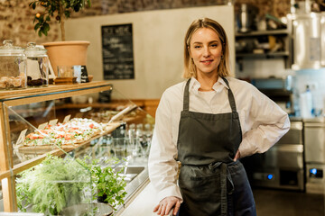 Entrepreneur standing proudly in cafe bistro with fresh food display
