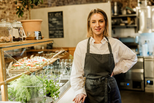 Entrepreneur standing proudly in cafe bistro with fresh food display