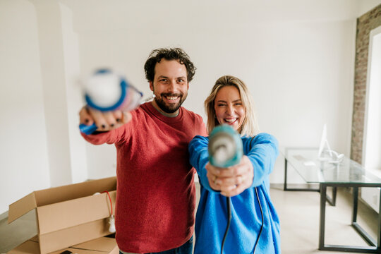 Couple smiling and holding tools indoors during home renovation