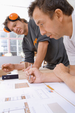 Carpenter drawing and planning at workshop table with blueprint