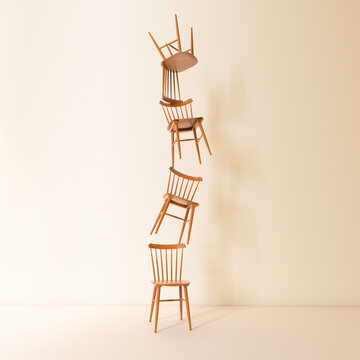 Stacked wooden chairs balancing indoors representing teamwork and stability