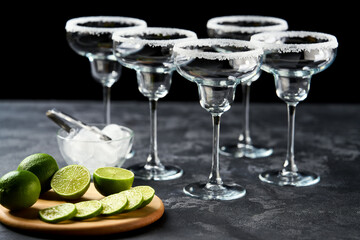 Bar accessories and ingredients for prepared cocktail Margarita on a black table.
