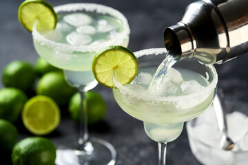 Margarita cocktail is poured from a shaker into a glasses and lime and salt rim , selective focus.