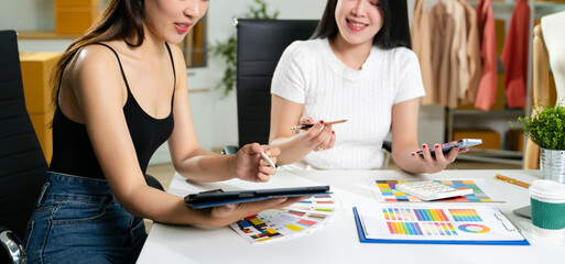 Fashion designers working together in a studio with color palettes, tablet, and sketches. Creative teamwork, modern workspace, textile planning