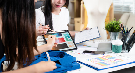 Fashion designers working together with fabric and color palette on digital tablet. Creative teamwork, textile planning and modern fashion studio concept