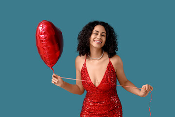 Young African-American woman with heart-shaped balloon on blue background. Valentine's day...
