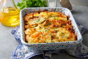 Potato gratin - graten (baked potatoes with cream and cheese) with rosemary and forks (Turkish name; Kremali patates)