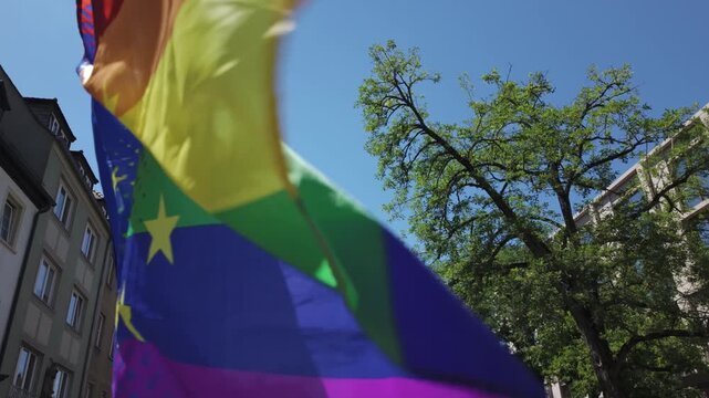 W&Uuml;RZBURG, GERMANY - JUN 28, 2025: Close-up slow motion of a colourful LGBTQ+ rainbow flag with yellow European Union stars waving by the wind at the Christopher Street Day (CSD) celebration and demo.
