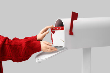 Hands taking letter from mailbox on light background. Valentine's Day celebration