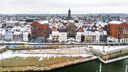 Snowy Venlo town waterfront near Maas river aerial drone view, winter cityscape with rooftops covered with snow, winter weather in Limburg, the Netherlands