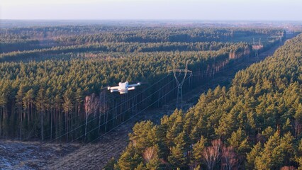 Drone flight over a high-voltage electricity pylon at sunset.