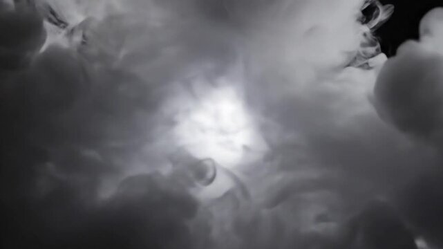 Abstract white smoke puff explosion spreading on a black background revealing brightness.