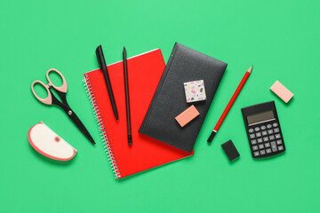Different rubber erasers with notebooks and stationery on green background
