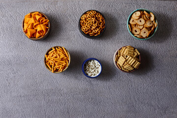 Assorted snacks in pottery bowls on grey background