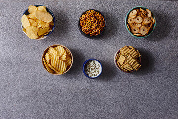 Assorted snacks in pottery bowls on grey background