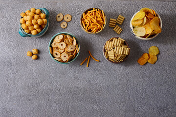 Assorted snacks in pottery bowls on grey background