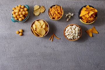 Assorted snacks in pottery bowls on grey background