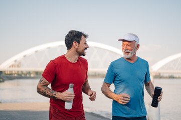 Father and son jogging together by the river, sharing a moment of joy and fitness