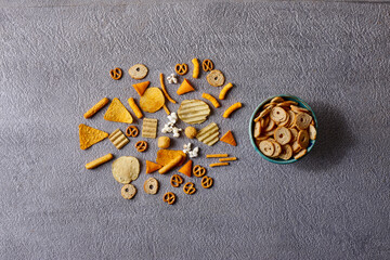 Assorted snacks in pottery bowls on grey background