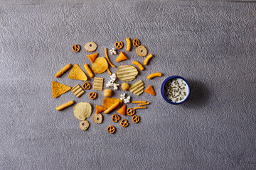 Assorted snacks in pottery bowls on grey background