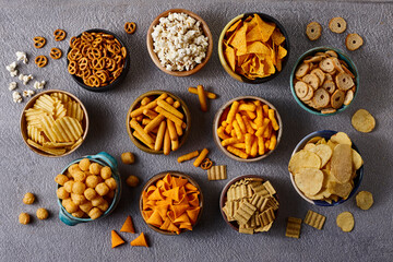 Assorted snacks in pottery bowls on grey background