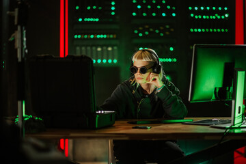 Young hacker wearing goggles working in dark server room