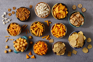 Assorted snacks in pottery bowls on grey background