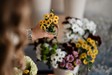 Woman's hand holding yellow chrysanthemum flowers arranging bouquet