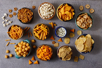 Assorted snacks in pottery bowls on grey background