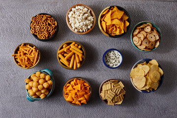 Assorted snacks in pottery bowls on grey background
