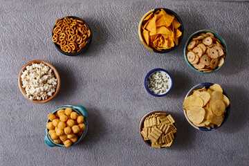 Assorted snacks in pottery bowls on grey background