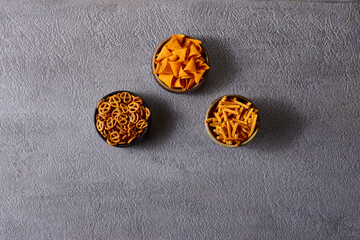 Assorted snacks in pottery bowls on grey background