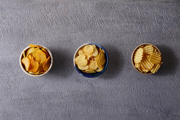 Assorted snacks in pottery bowls on grey background