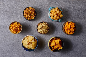 Assorted snacks in pottery bowls on grey background