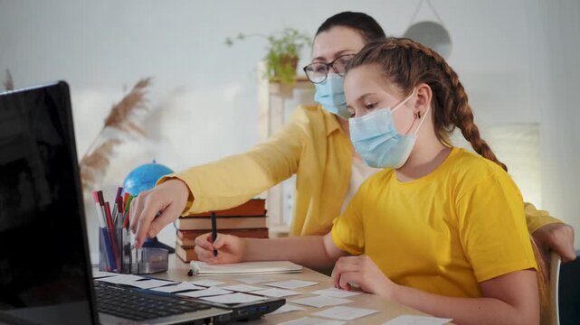 Tutor guides student with mask during study session at laptop in classroom homeschool setting, teacher assisting with homework, tutor support for focused learning, education and skill development.