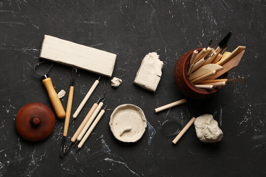 Composition with set of sculptor tools and clay on black grunge background