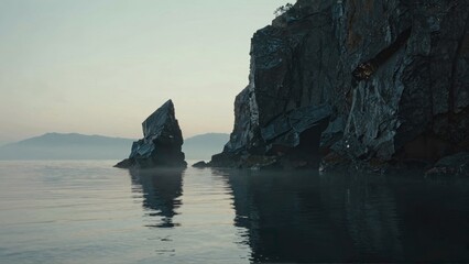 Rocky cliffs reflecting in calm sea with distant mountains