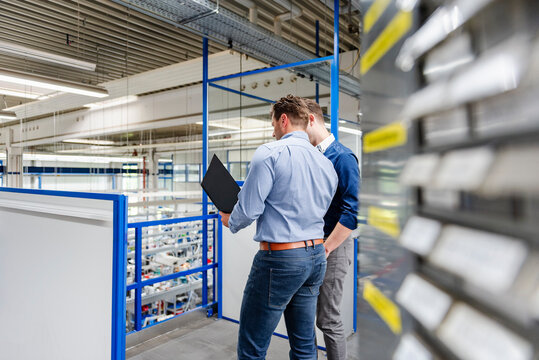 Colleagues meeting in production hall discussing business organization
