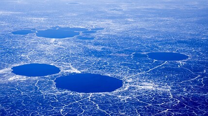 Aerial view of a frozen arctic expanse with several dark blue, open water pools