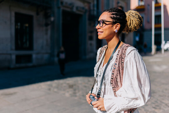 Tourist with camera smiling outdoors at Plaza de la Villa Madrid