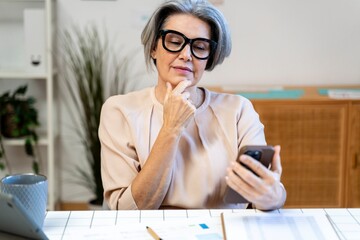 Professional thinking and planning with smartphone at workspace