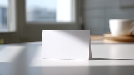 Blank card sits on table, next to mug, with light from window