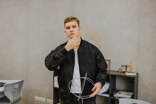 Student posing thoughtfully with geometric figure in classroom