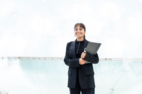 Confident businesswoman posing outdoors in office suit with modern building