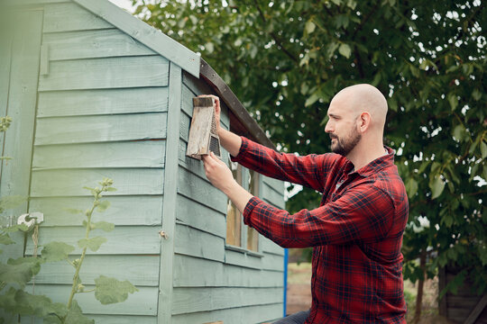 Person adjusting a bug hotel on garden shed in allotment outdoors