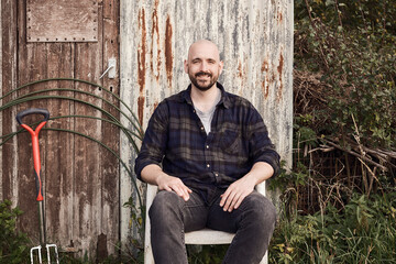 Portrait of man sitting at rustic allotment shed in London outdoors