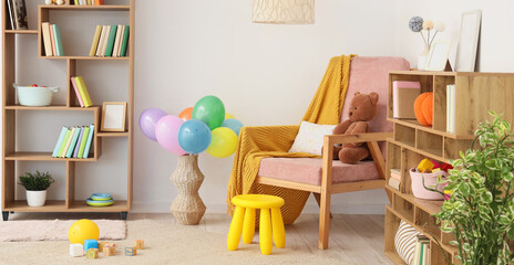 Interior of light children's room with bookshelves, armchair and toys © Pixel-Shot