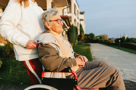 Woman in wheelchair assisted outdoors showing support and care