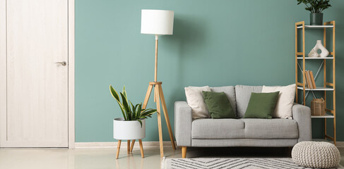 Interior of stylish living room with grey sofa, shelf unit and lamp